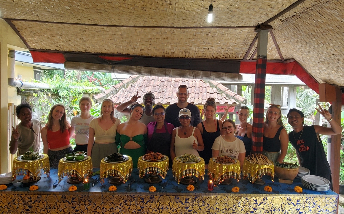 Group cooking class posing behind a table of prepared dishes.