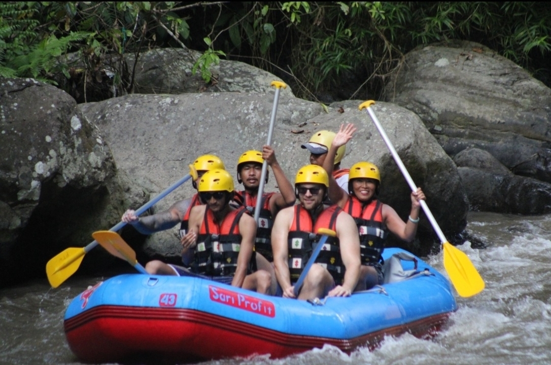Group of rafters in protective gear navigating a river.
