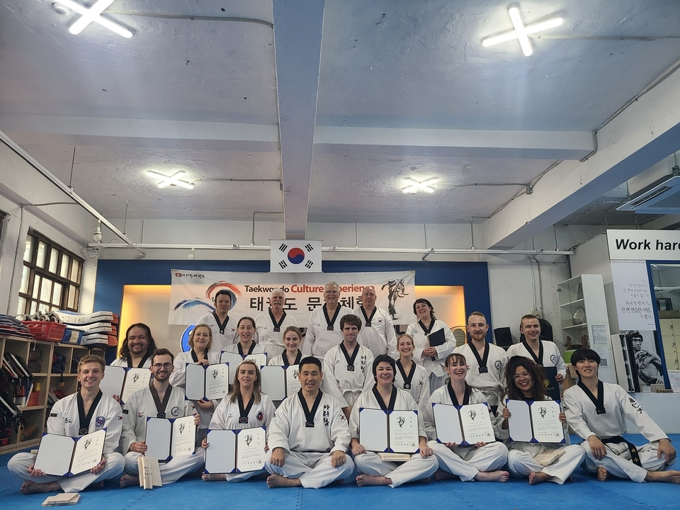 Photo de groupe de personnes portant des uniformes de Taekwondo avec des certificats.