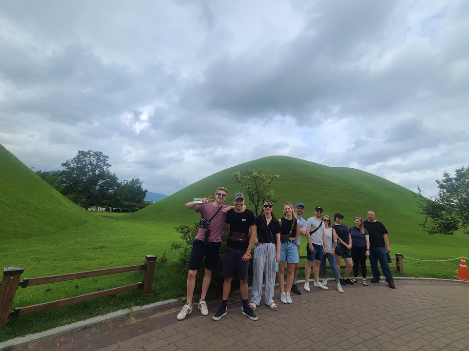Groep mensen die poseren met groene heuvels op de achtergrond.