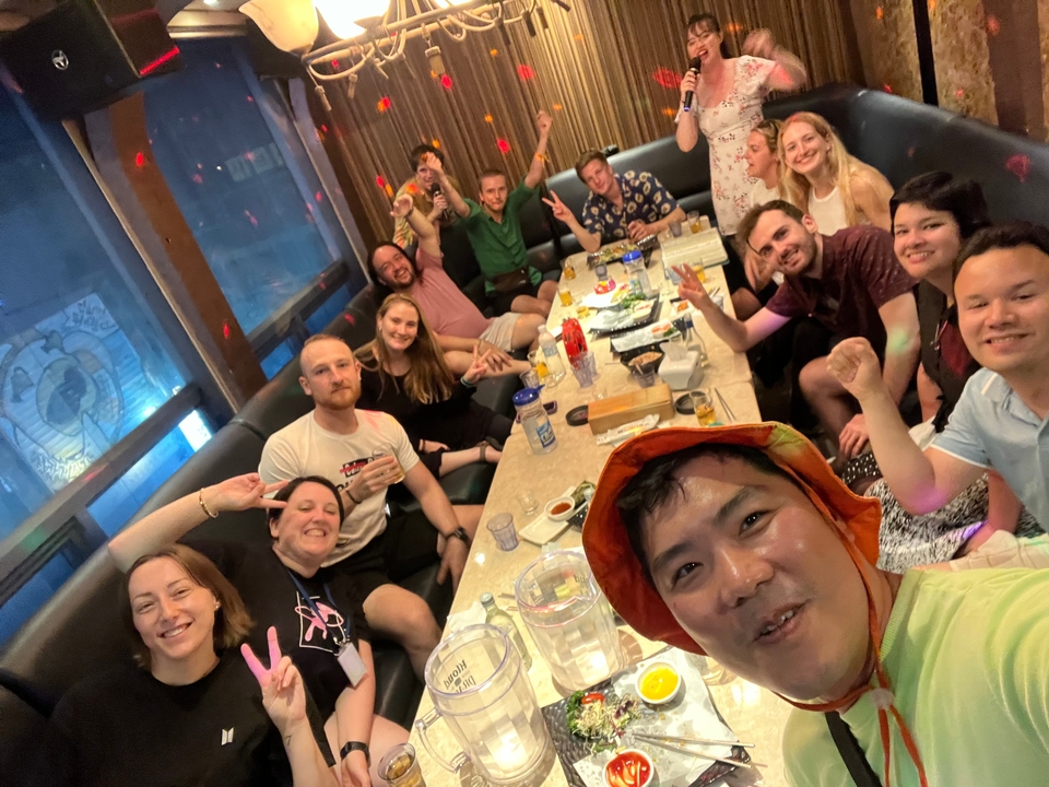 Groep mensen die vredestekens maken aan een eettafel.