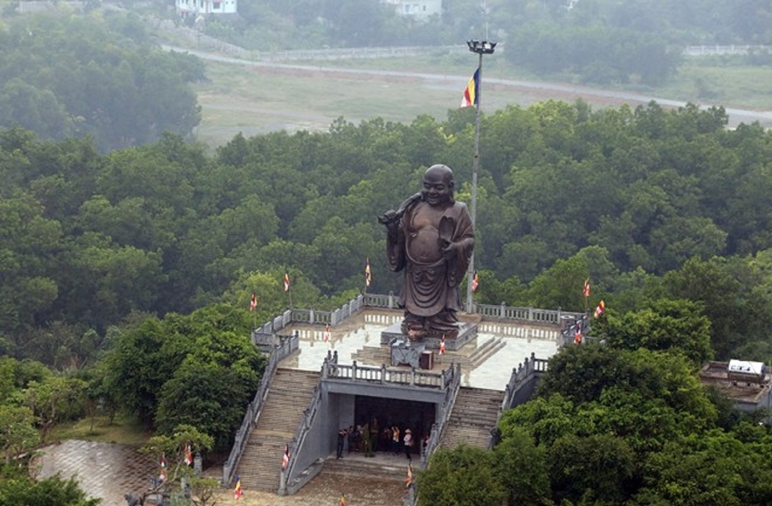 Large Buddha statue overlooking a forested area.