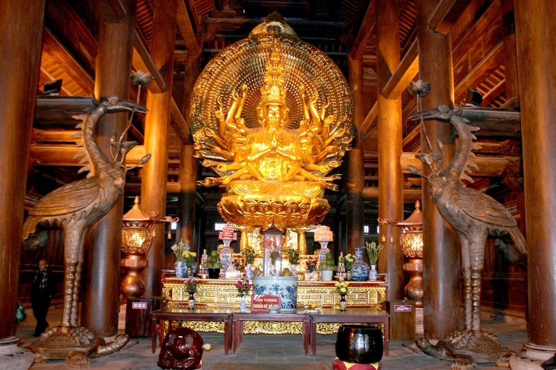 Golden statue of multiple arms inside a temple.