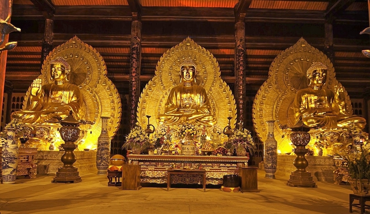 Three golden Buddha statues inside a temple.