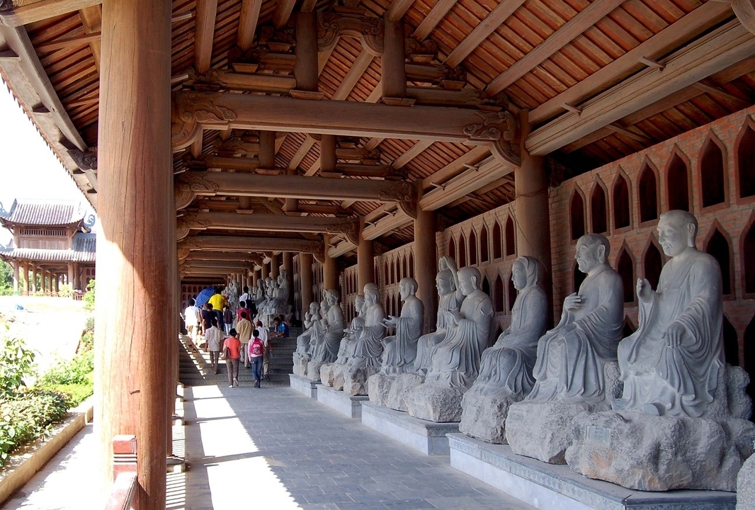 Corridor of statues with people walking through.