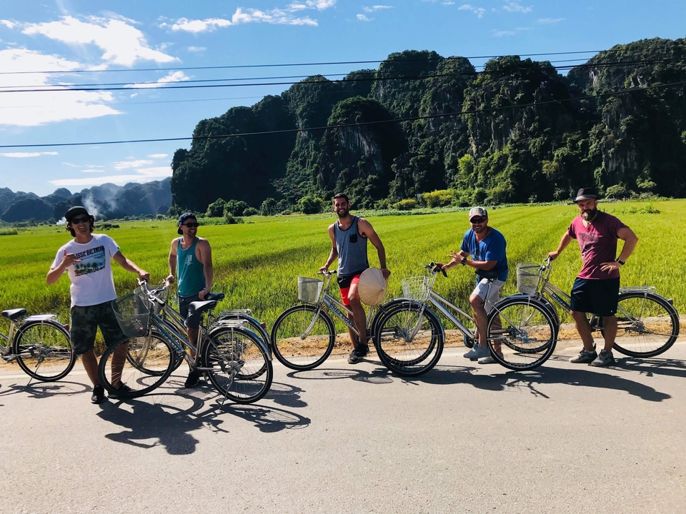 Group of friends standing next to bicycles in a rural setting.