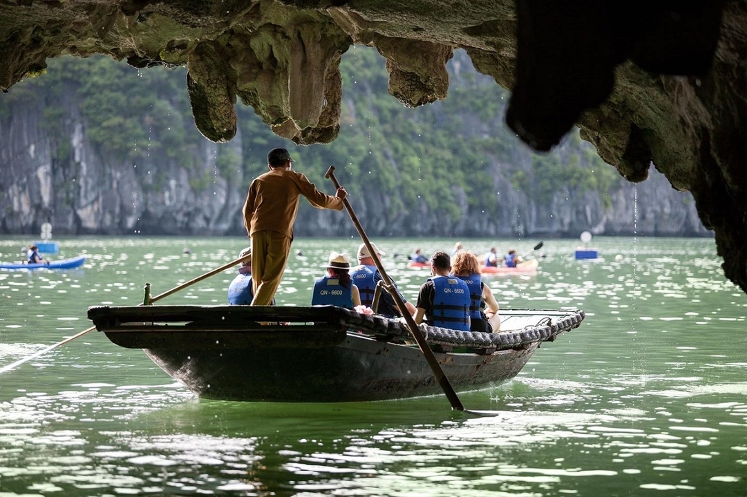 Des personnes lors d'une excursion en bateau à travers l'ouverture d'une grotte avec des falaises de calcaire visibles.