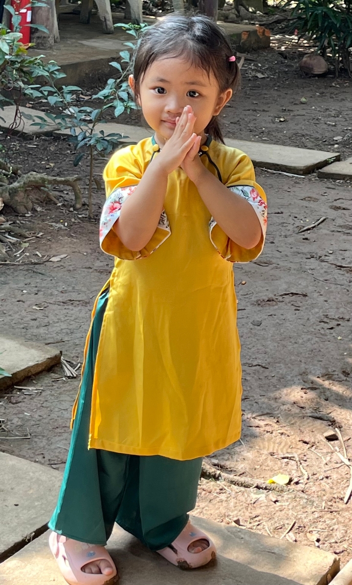 Enfant en robe traditionnelle jaune avec les mains jointes