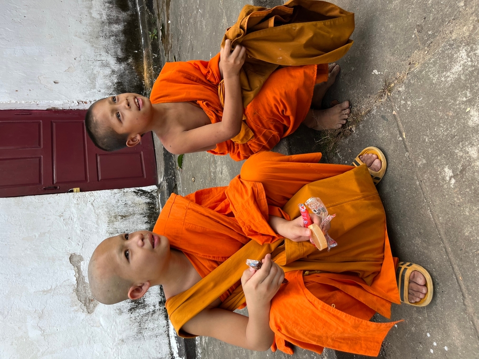 Jeunes moines en robes orange assis par terre