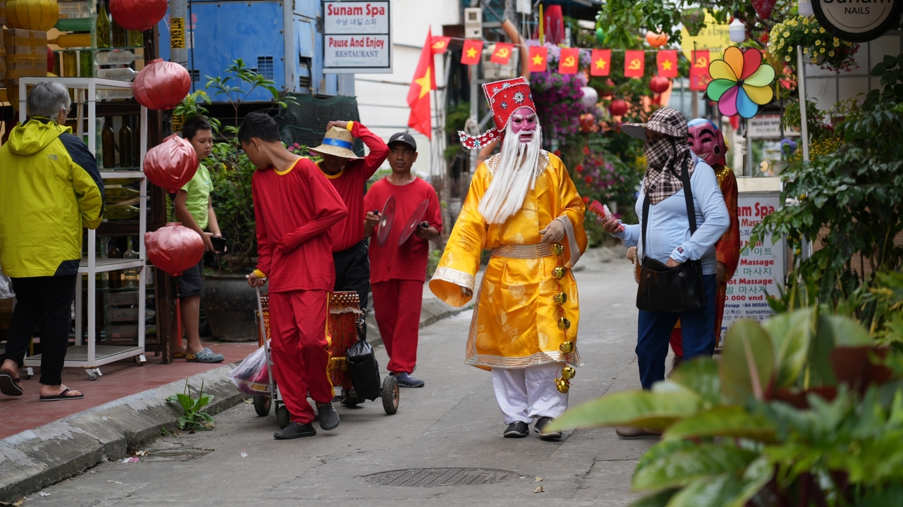 People in colorful traditional costumes walking down a street with decorations.
