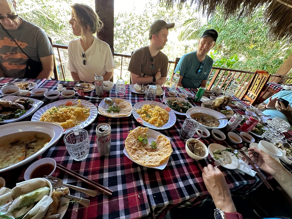 Group of people enjoying a meal at a table filled with various dishes.