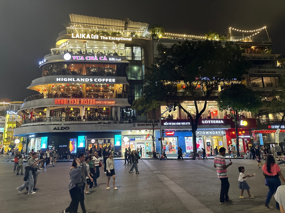 Busy city street with people and lit commercial buildings at night.