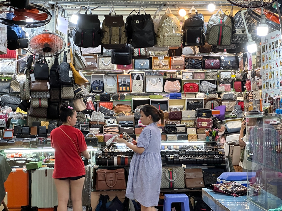 Women shopping for bags at a busy market stall.