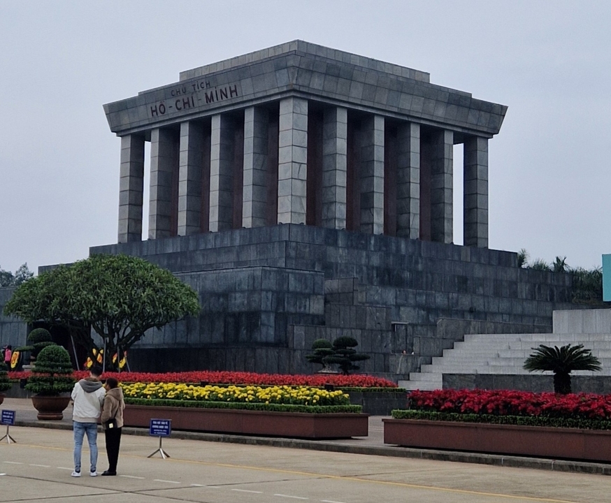 Ho Chi Minh Mausoleum with visitors and gardens in foreground.