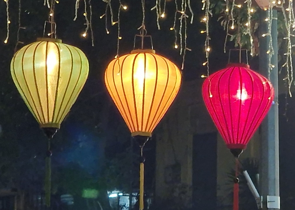 Three traditional lanterns lit up at night.