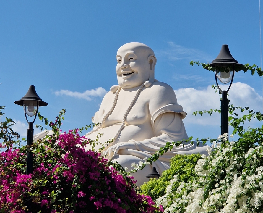 Large Buddha statue surrounded by flowers and lights.