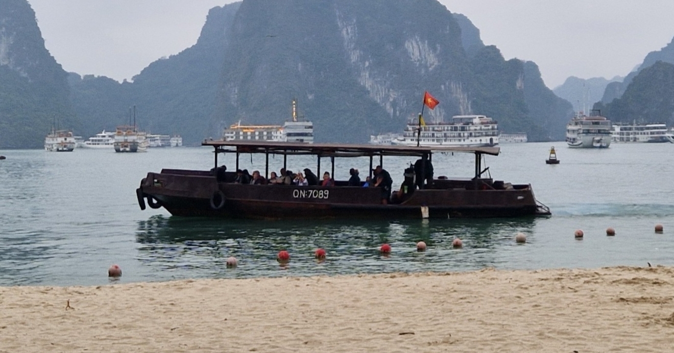 Boat with passengers on the water with limestone cliffs in the background.