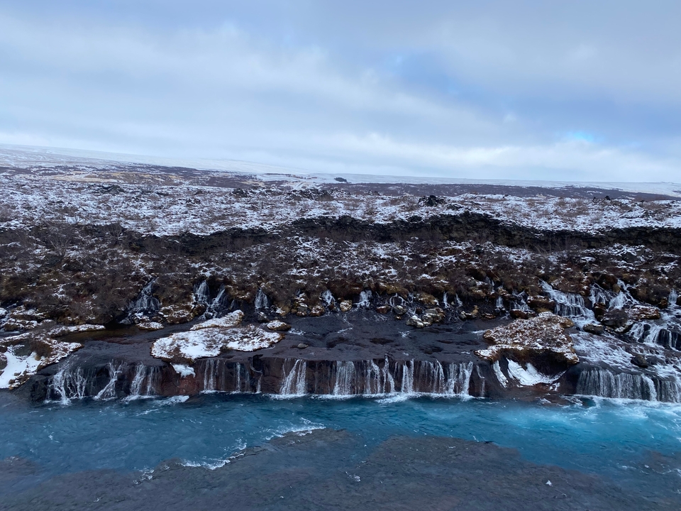 Waterfall flowing over rocks in a winter landscape.