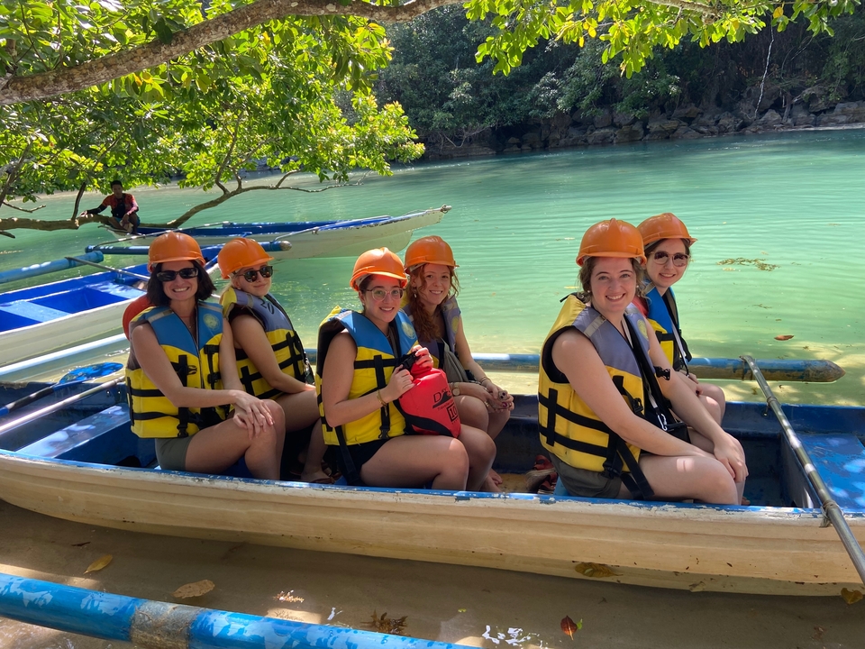 Groupe de personnes dans un bateau portant des casques et des gilets de sauvetage.