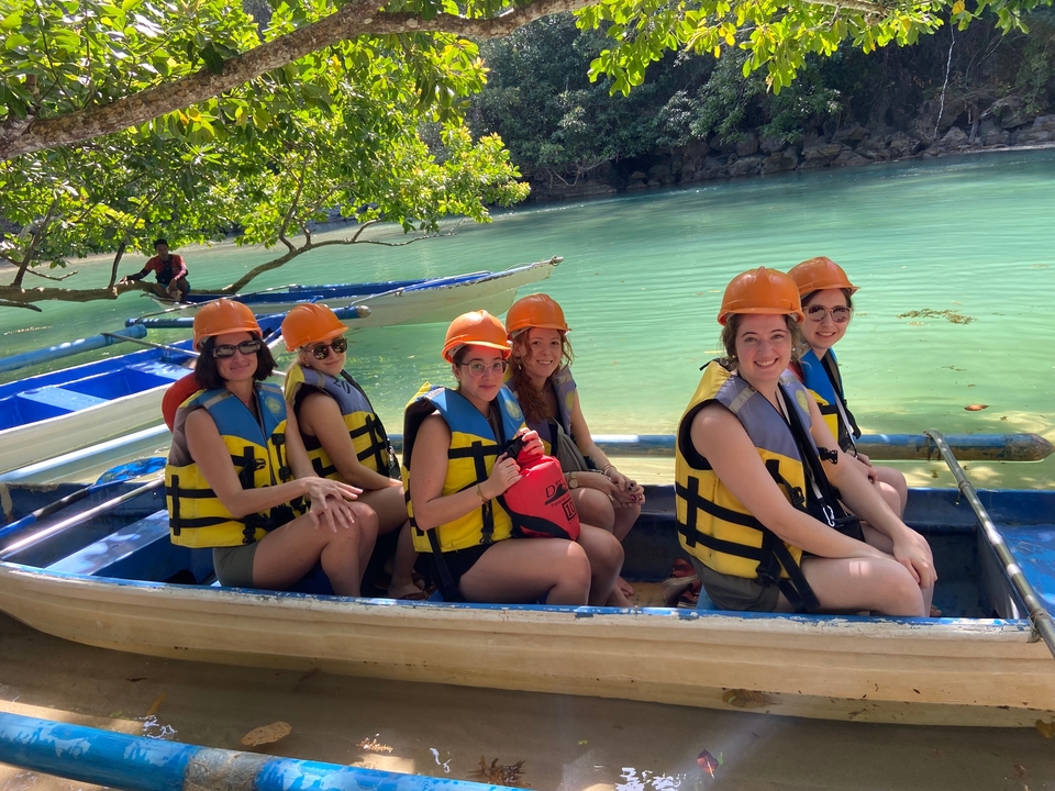 Groupe de personnes dans un bateau portant des casques et des gilets de sauvetage.