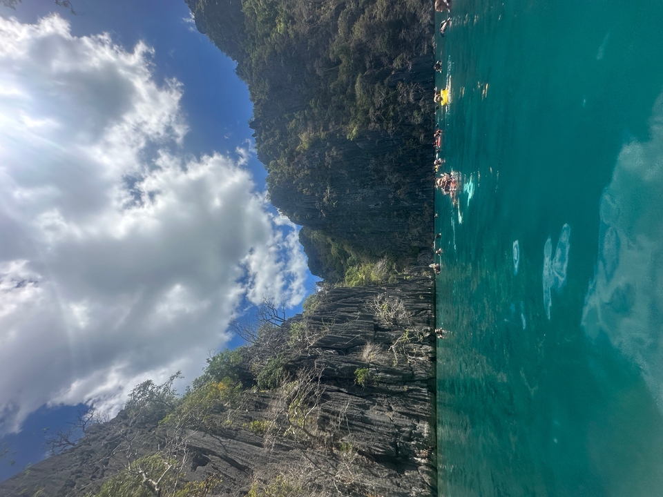 Des gens qui nagent près de falaises et d'une eau turquoise.