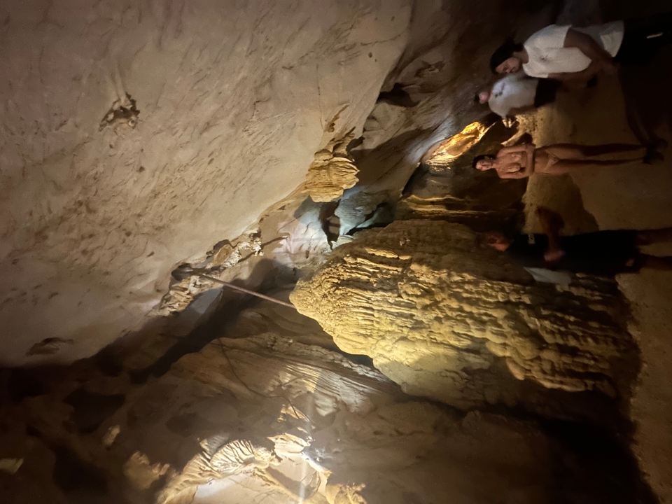 Des personnes explorant une grotte faiblement éclairée.