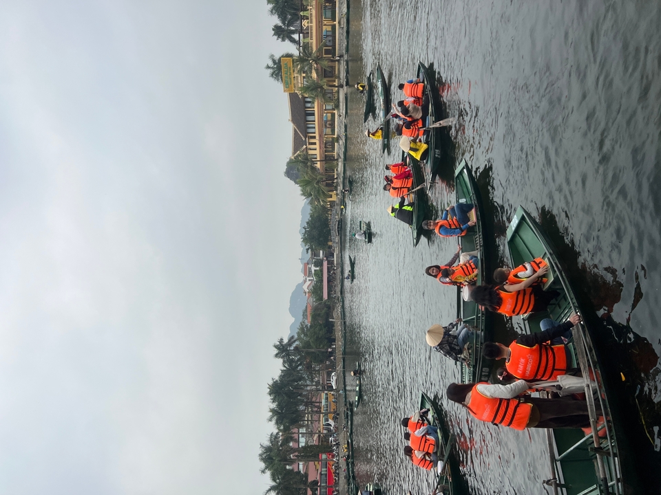 Des gens en gilets de sauvetage orange sur des bateaux dans un lac.