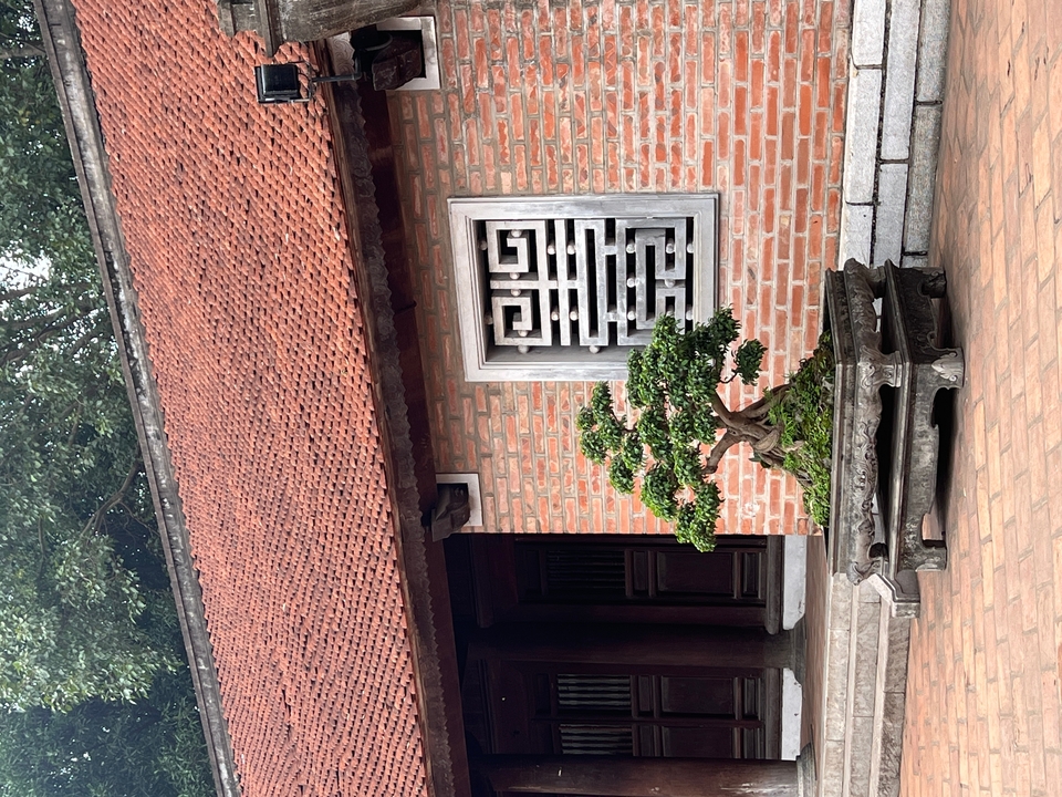 Un bâtiment traditionnel avec un bonsaï et un design de fenêtre complexe.
