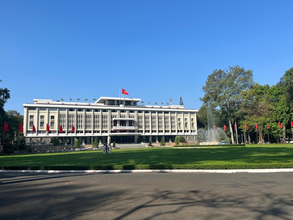 Un bâtiment imposant avec des drapeaux devant et une fontaine sur le côté.