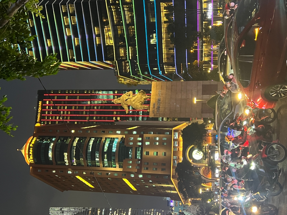 Une rue animée la nuit avec des bâtiments illuminés et des motos.