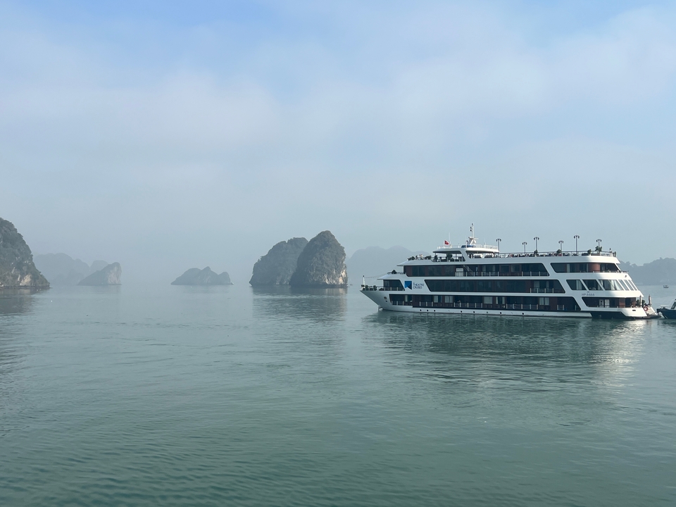 Un grand navire de croisière sur les eaux calmes avec des karsts calcaires en arrière-plan.