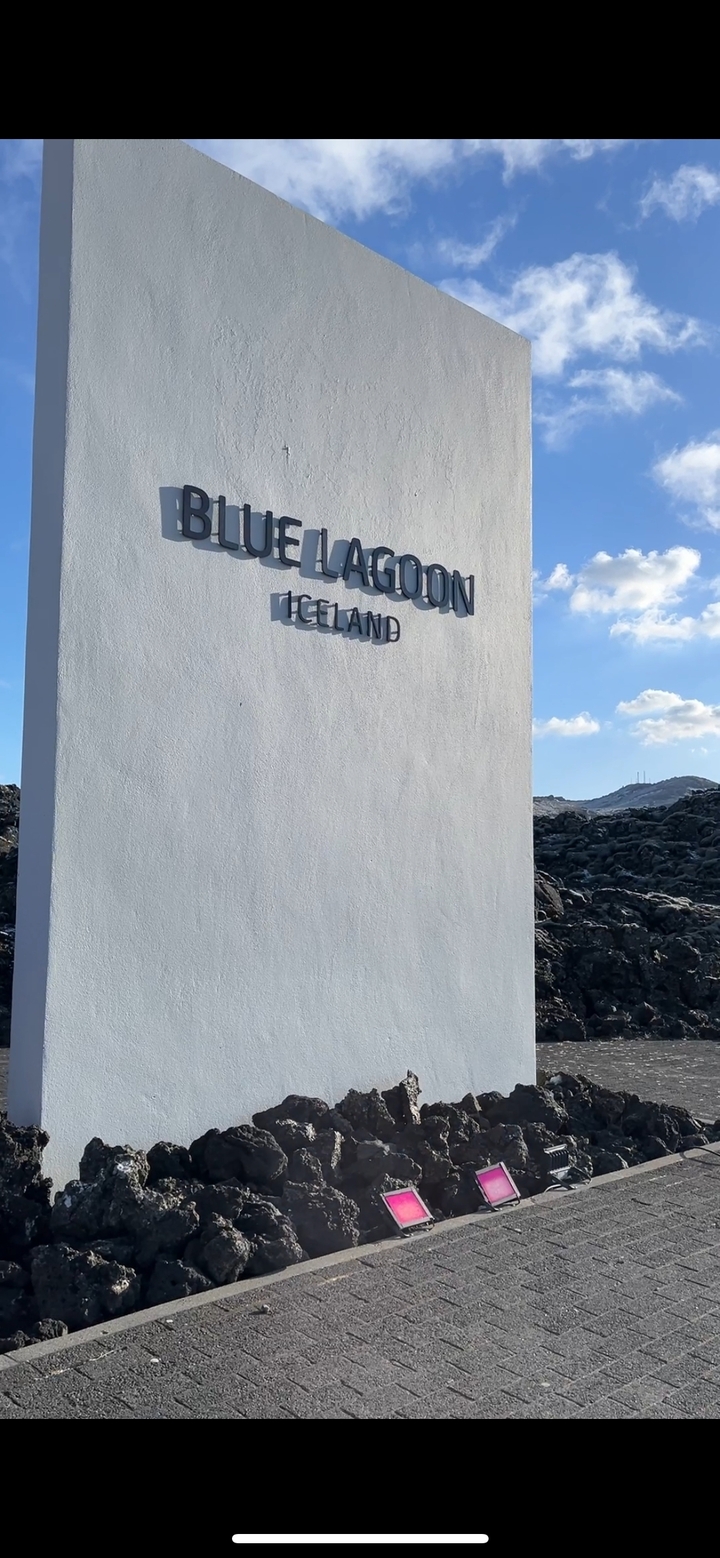 Sign reading 'Blue Lagoon Iceland' against a rocky landscape.