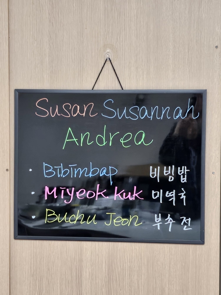 Panneau de menu sur tableau noir avec des plats listés en anglais et en coréen.