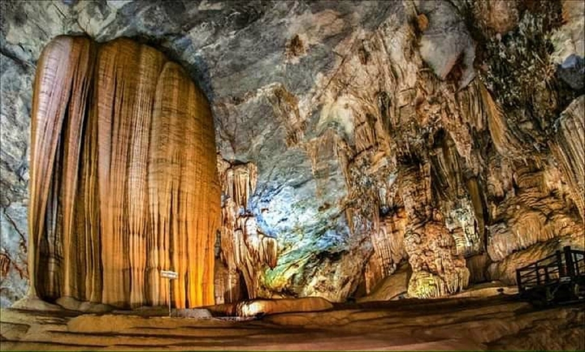 Intérieur de grotte illuminé avec de grandes stalactites.