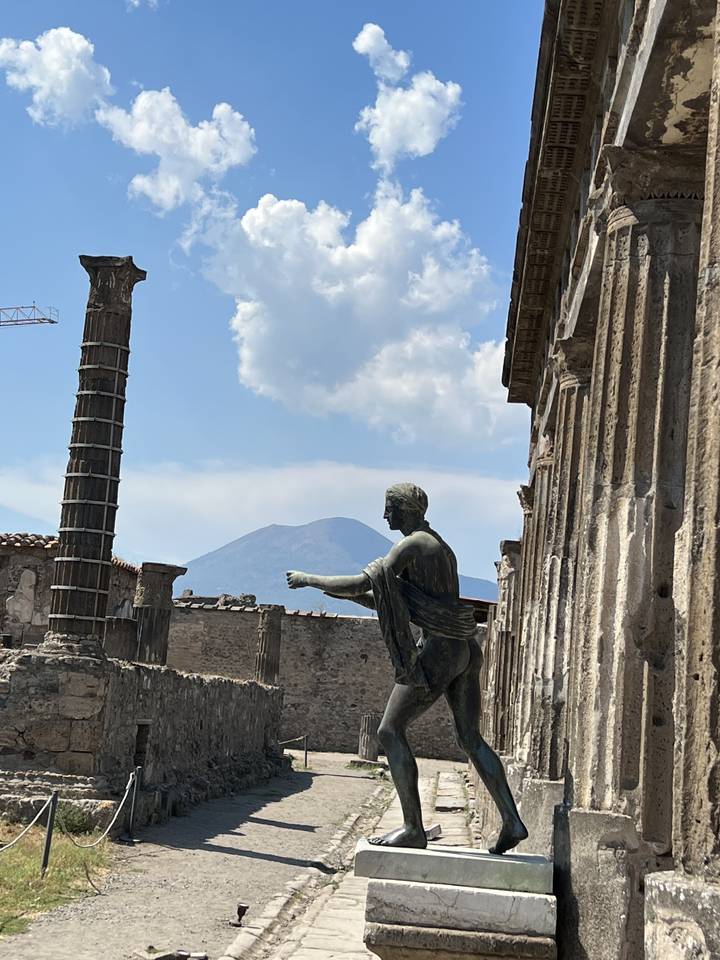A sculpture in a historic setting with a mountain in the background.
