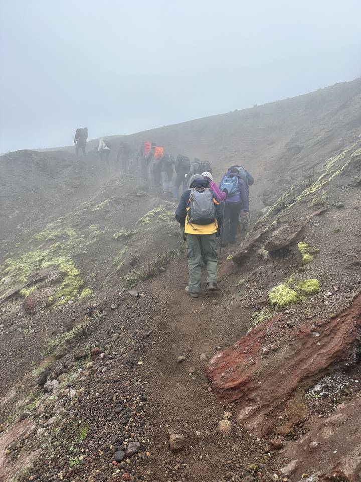 Hikers trekking up a rocky and foggy hillside.
