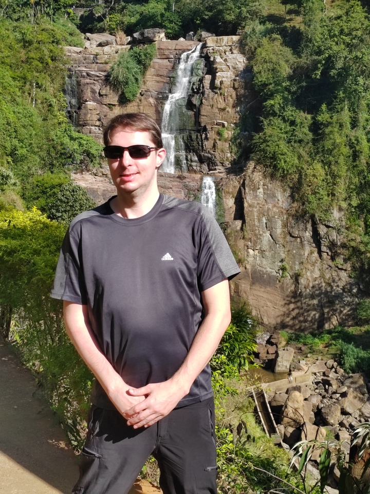 Personne qui pose devant une cascade.