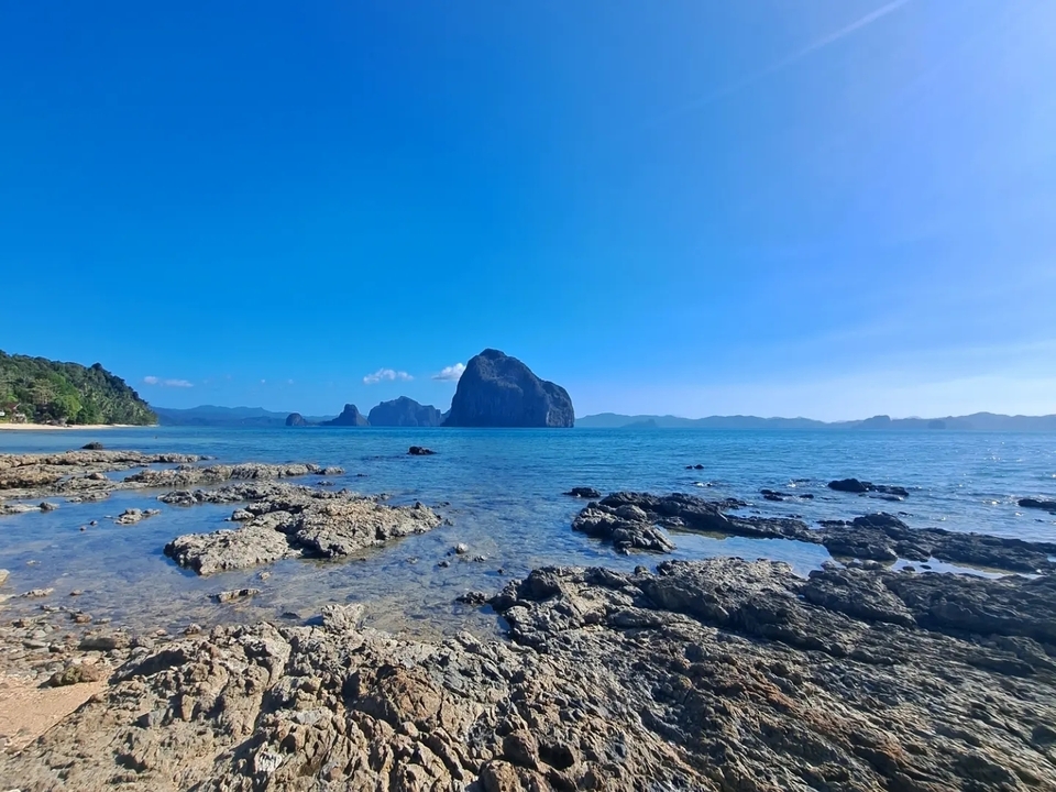 Paysage rocheux en bord de mer avec eau bleue et ciel dégagé.