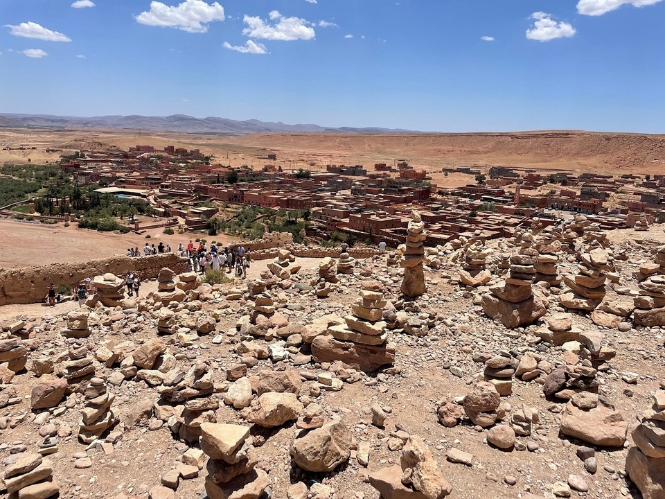 Vue panoramique d'un village désertique avec des pierres empilées au premier plan.