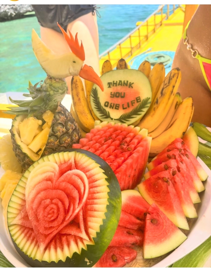 Plateau de fruits avec texte gravé, incluant ananas et pastèque.