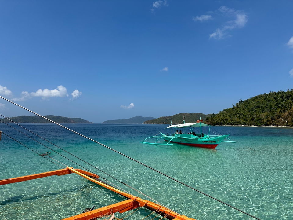Paysage tropical avec eau turquoise, un bateau et des îles.