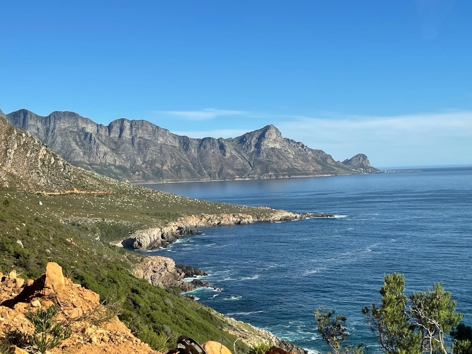 Coastal landscape with mountains and sea under a clear blue sky.