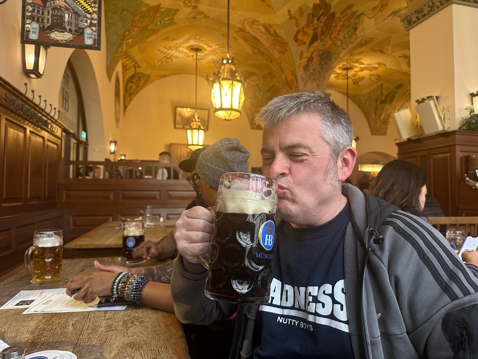 Homme buvant une grande chope de bière dans un restaurant traditionnel.