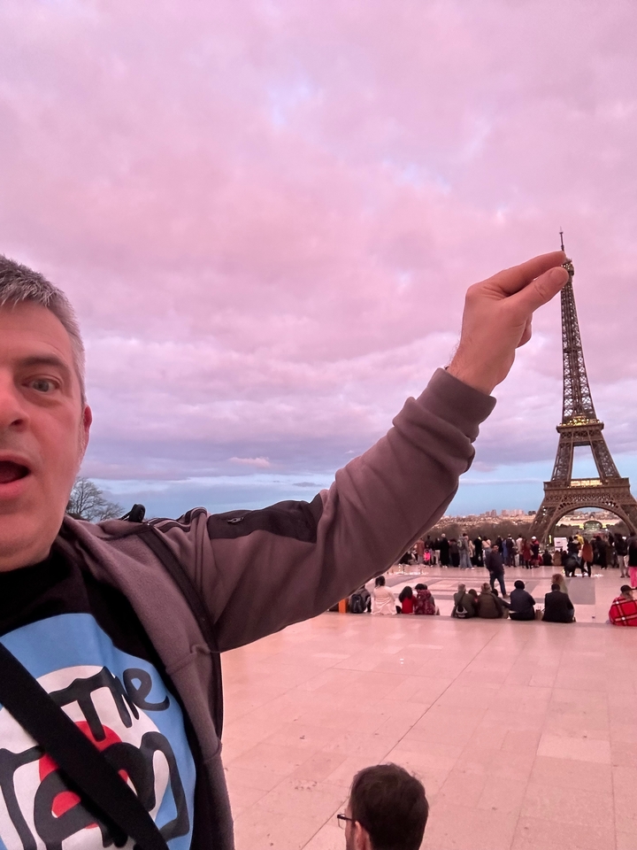 Personne posant avec humour avec la Tour Eiffel en arrière-plan.