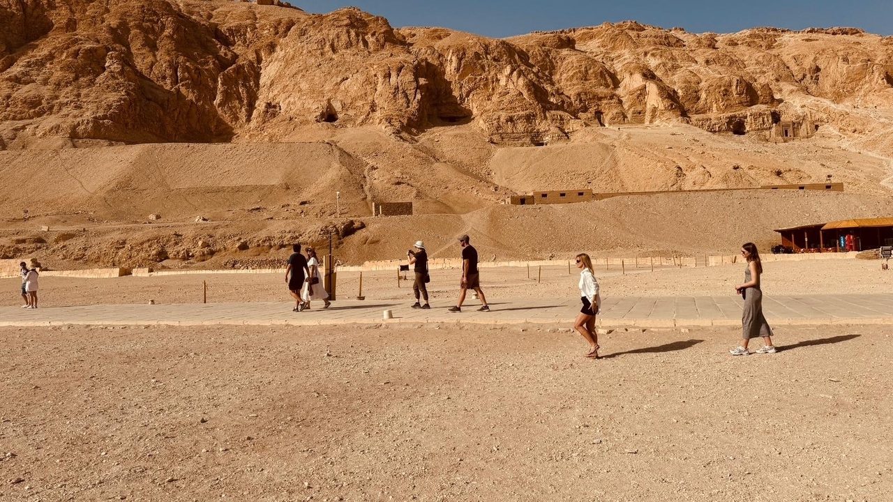 Groupe de personnes marchant dans un site archéologique sablonneux.