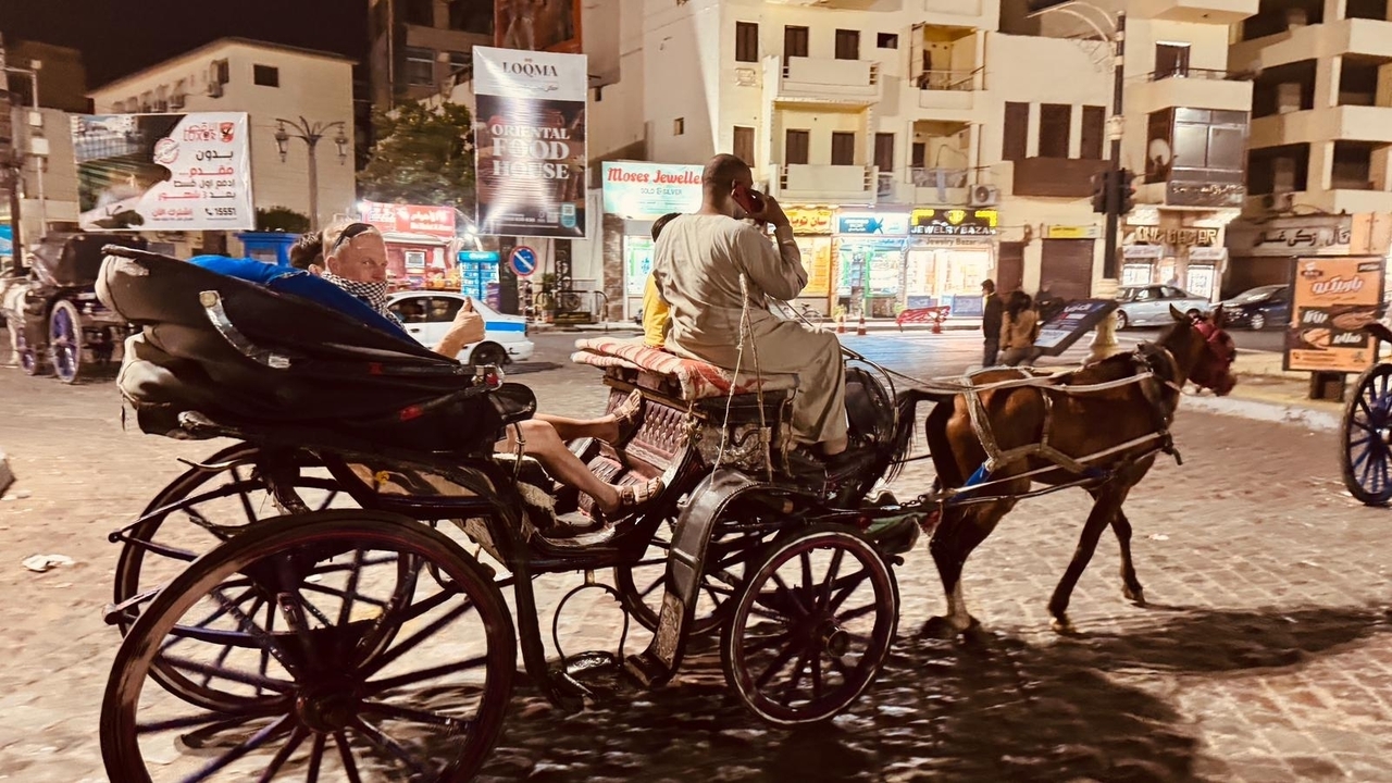 Calèche tirée par des chevaux avec des personnes dans une rue de la ville la nuit.