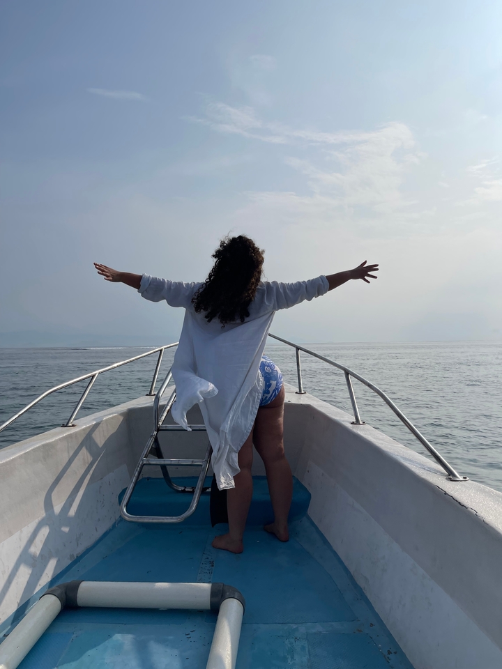 Person with arms outstretched on a boat.