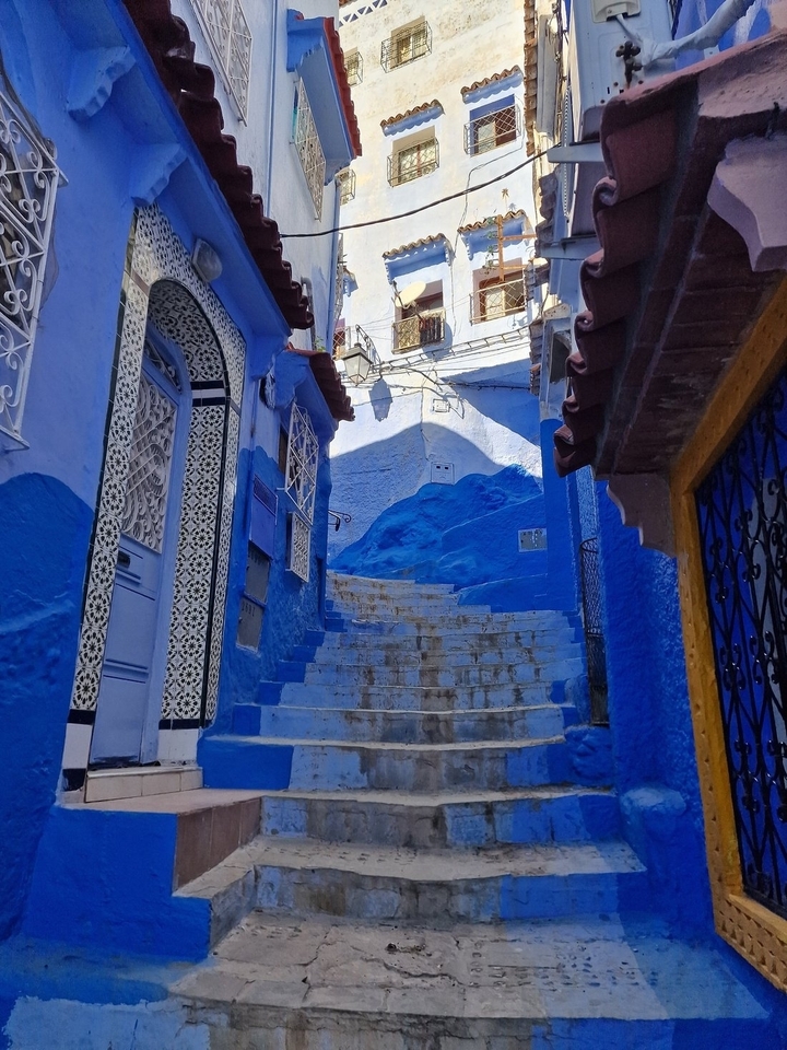 Narrow alley with blue painted walls and steps in a medina.