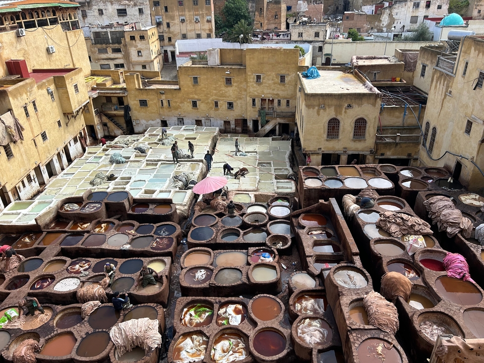 Tannerie avec cuves et ouvriers dans un paysage urbain historique.