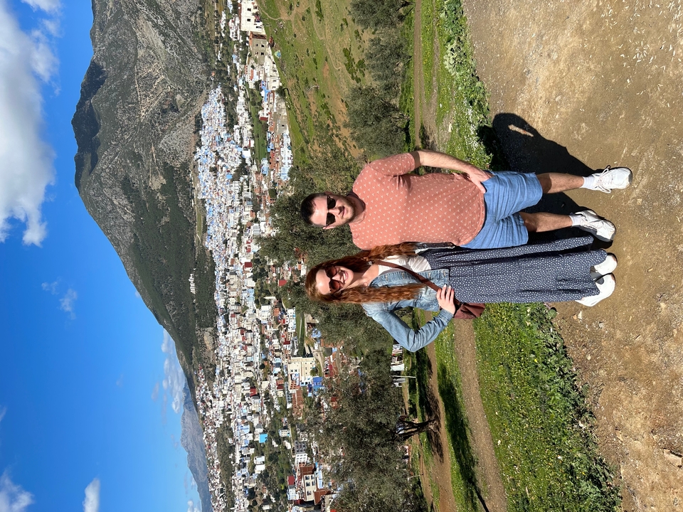 Deux personnes posant avec une vue sur une ville de colline bleue et blanche.
